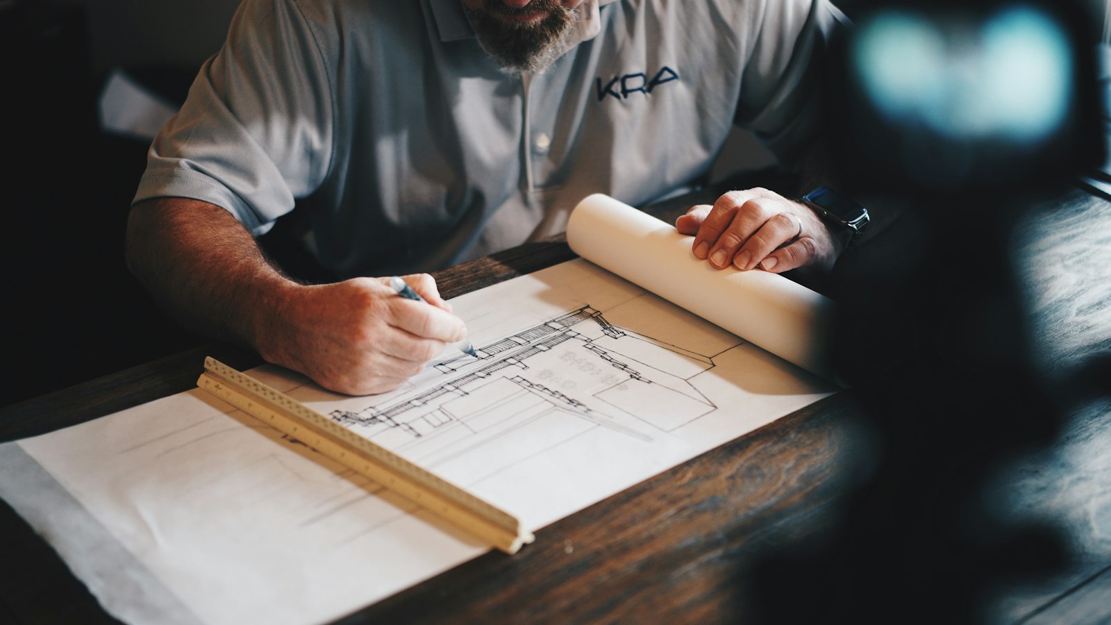 Estimator working on construction drawings with a pencil and ruler, measuring for a quantity takeoff